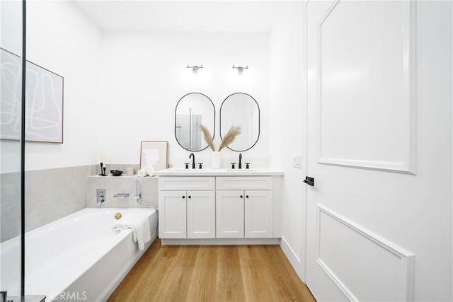 bathroom with vanity, wood-type flooring, and a tub to relax in