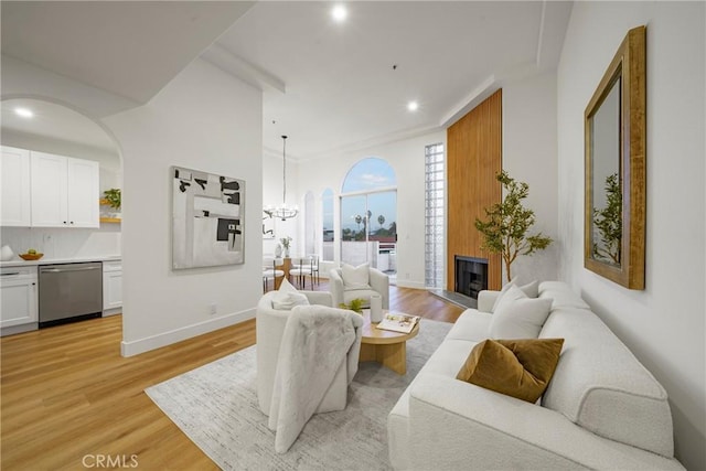 living room with a fireplace, light wood-type flooring, and a chandelier