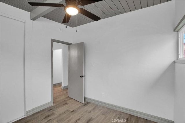 unfurnished room featuring wooden ceiling, ceiling fan, light hardwood / wood-style floors, and beamed ceiling