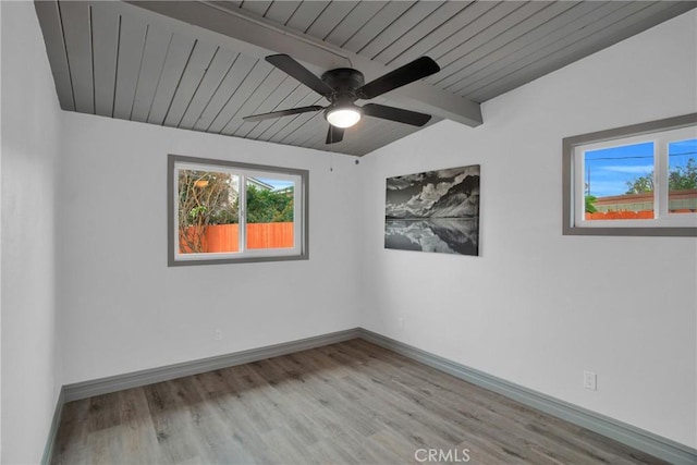 unfurnished room featuring ceiling fan, light wood-type flooring, and vaulted ceiling with beams