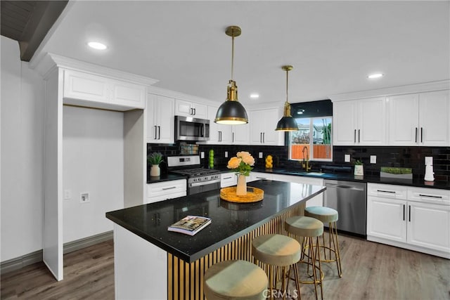 kitchen featuring a kitchen island, sink, appliances with stainless steel finishes, and white cabinetry