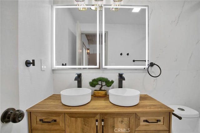 bathroom featuring toilet, vanity, and a chandelier