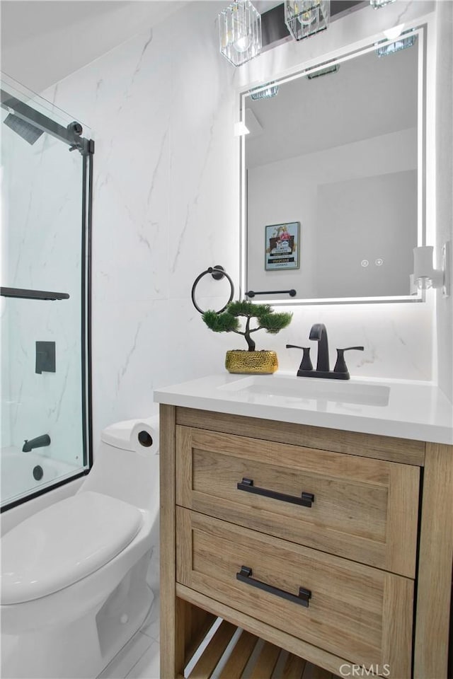 full bathroom with toilet, vanity, tile walls, and bath / shower combo with glass door