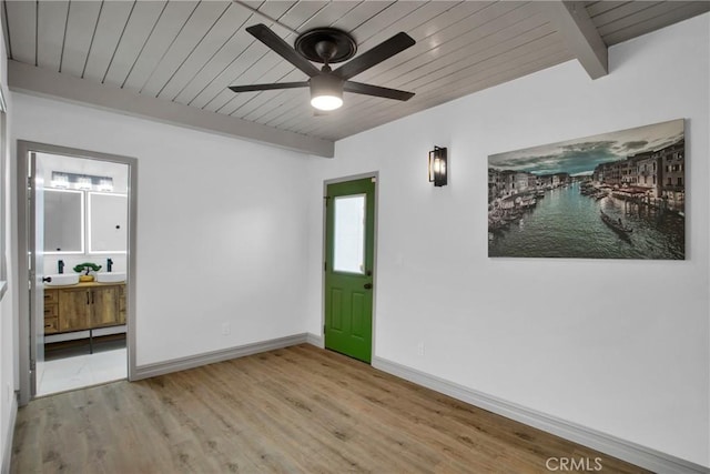 empty room featuring wood ceiling, light wood-type flooring, ceiling fan, beamed ceiling, and sink