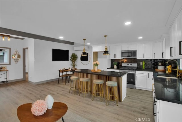 kitchen featuring white cabinets, stainless steel appliances, a kitchen bar, and a kitchen island