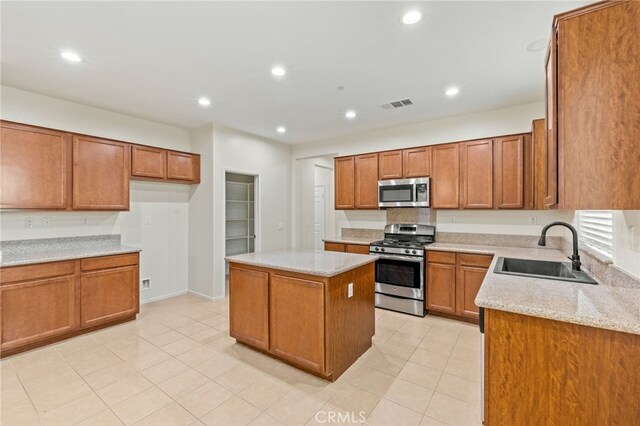 kitchen featuring light stone countertops, appliances with stainless steel finishes, a kitchen island, sink, and light tile patterned floors