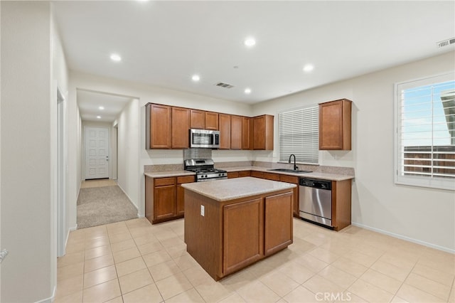 kitchen with light colored carpet, appliances with stainless steel finishes, sink, and a center island