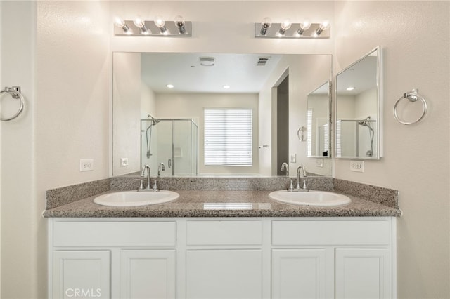 bathroom featuring a shower with shower door and vanity