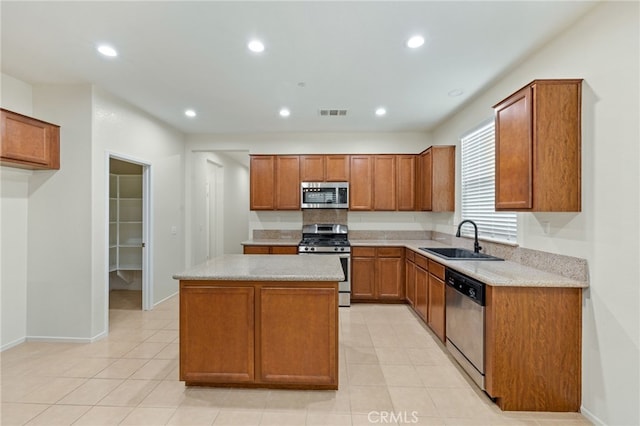 kitchen featuring light stone counters, sink, stainless steel appliances, and a kitchen island