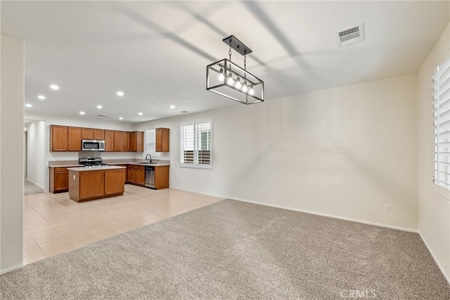 kitchen featuring stainless steel appliances, a center island, light tile patterned flooring, hanging light fixtures, and sink