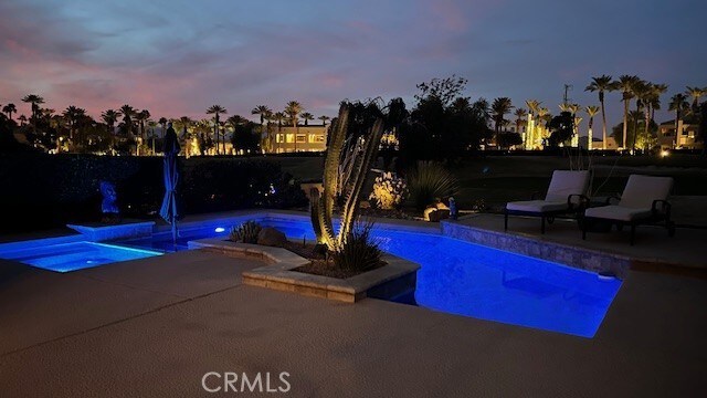 pool at dusk featuring a patio area