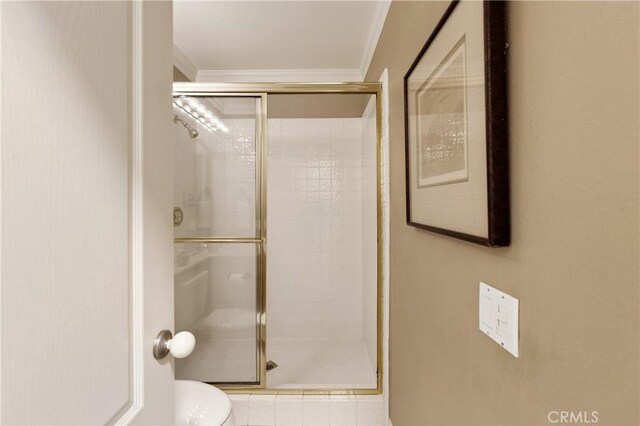 bathroom with an enclosed shower, ornamental molding, and toilet