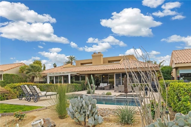28 Pebble Beach Dr, Rancho Mirage, CA 92270 - rear view of house with a sunroom, stucco siding, an outdoor pool, a patio area, and a tiled roof