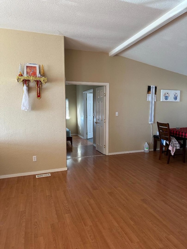 interior space featuring a textured ceiling, dark hardwood / wood-style flooring, and lofted ceiling with beams