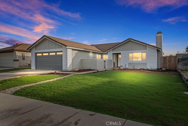 ranch-style home featuring a garage and a lawn