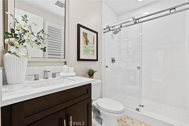 bathroom featuring toilet, a shower with shower door, and vanity