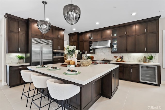 kitchen featuring light tile patterned floors, stainless steel built in fridge, decorative light fixtures, beverage cooler, and range hood