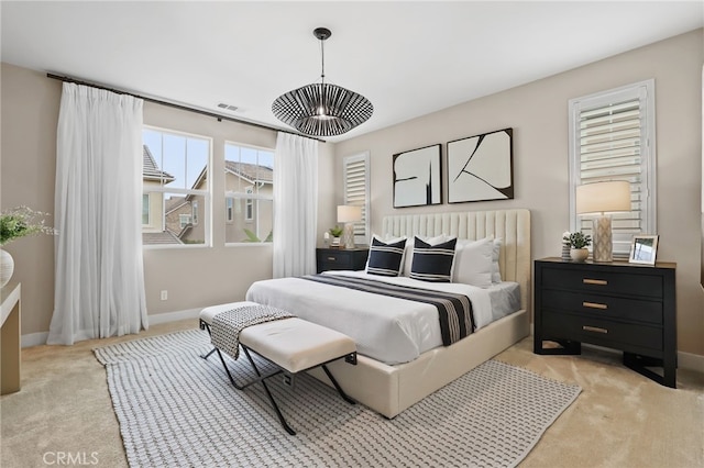 bedroom featuring light carpet and a chandelier