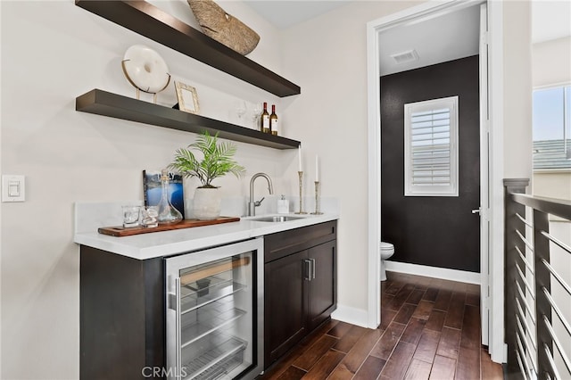 bar with sink, dark brown cabinetry, and wine cooler