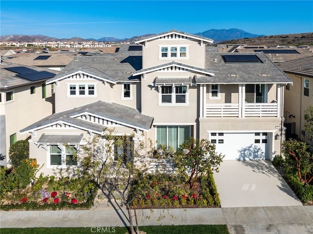 view of front facade with solar panels, a balcony, a mountain view, and a garage