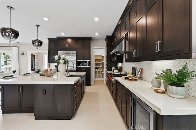 kitchen featuring appliances with stainless steel finishes, decorative light fixtures, tasteful backsplash, wine cooler, and light tile patterned floors