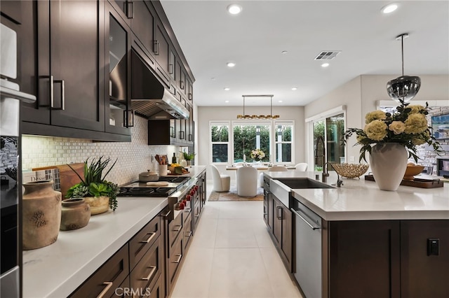 kitchen with dishwasher, decorative backsplash, hanging light fixtures, light tile patterned floors, and a center island with sink