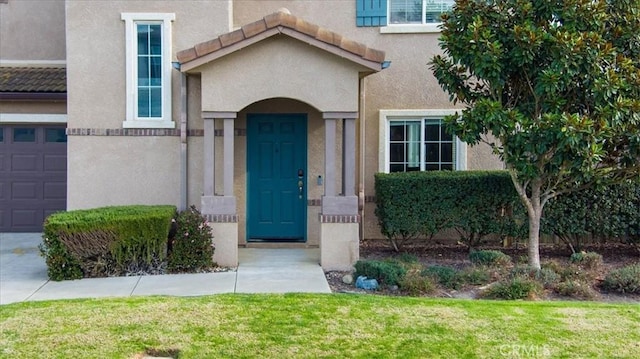 view of exterior entry with a garage and a lawn