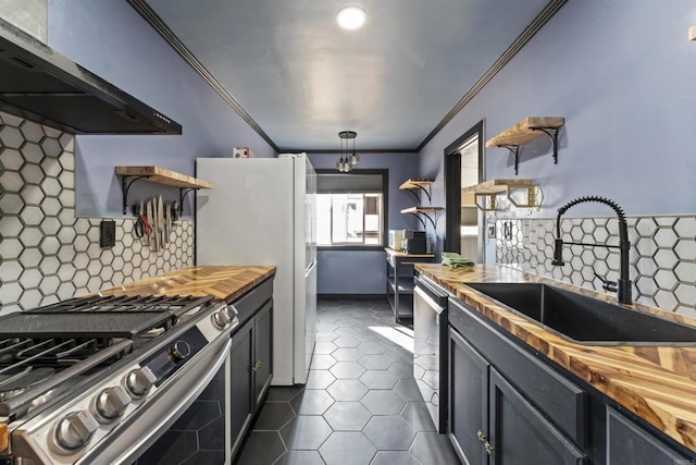 kitchen with wooden counters, stainless steel gas range, decorative backsplash, hanging light fixtures, and wall chimney exhaust hood