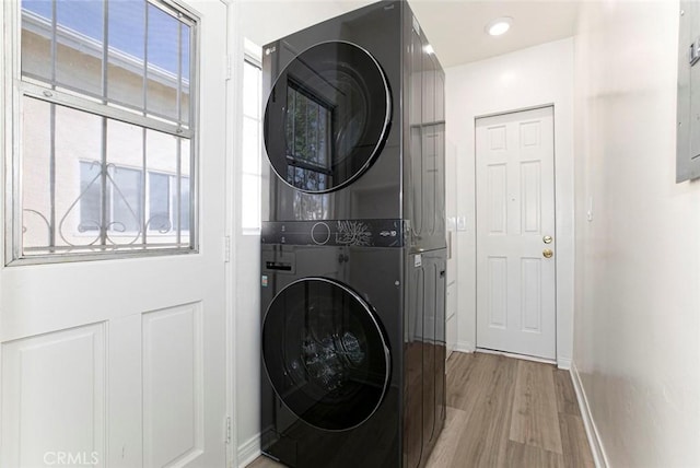 laundry area with stacked washer and dryer and light hardwood / wood-style floors