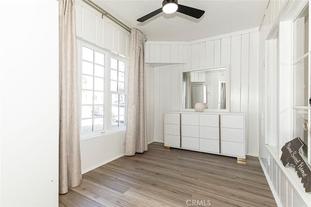 unfurnished bedroom featuring ceiling fan, light hardwood / wood-style floors, and wood walls