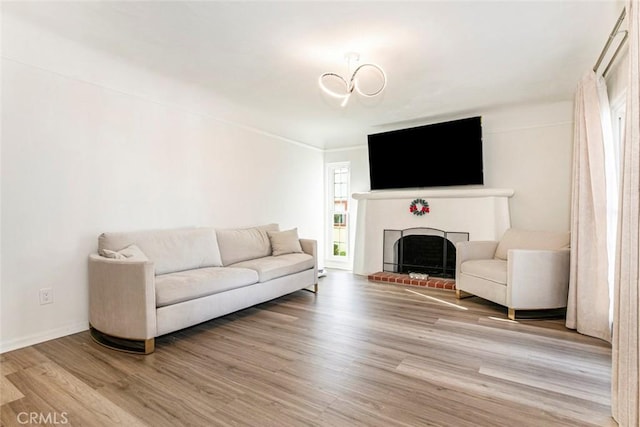 living room featuring light wood-type flooring, an inviting chandelier, and a fireplace