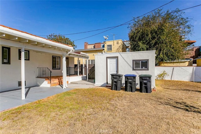 back of house with a lawn and a patio