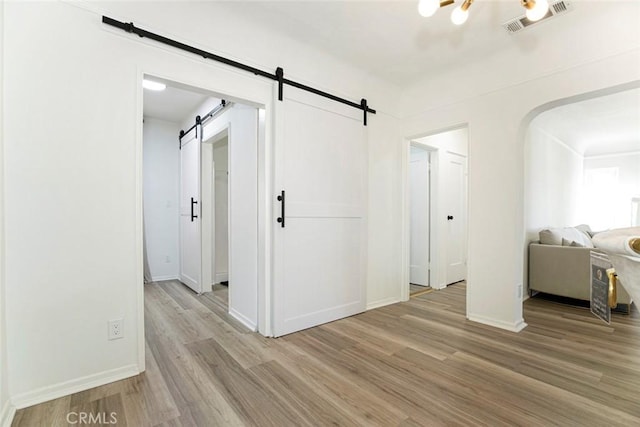 spare room with light hardwood / wood-style floors and a barn door