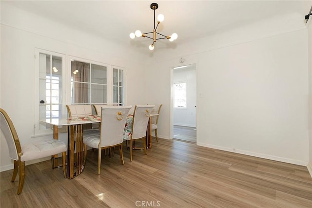 dining space with an inviting chandelier, light hardwood / wood-style floors, and a barn door