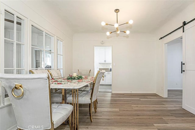 dining room with a chandelier, wood-type flooring, and a barn door