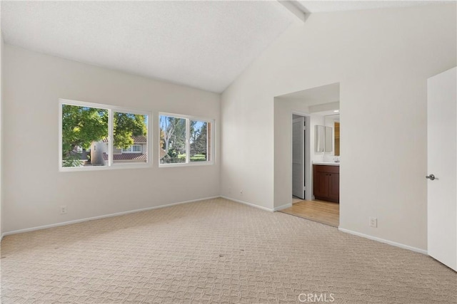 carpeted empty room featuring vaulted ceiling with beams