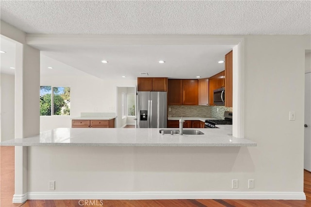 kitchen with light stone counters, sink, appliances with stainless steel finishes, and kitchen peninsula