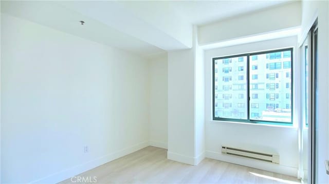 spare room with light hardwood / wood-style floors and a baseboard radiator