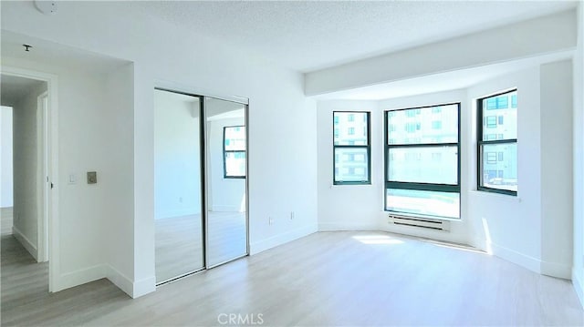 unfurnished bedroom with light wood-type flooring, a closet, and a textured ceiling