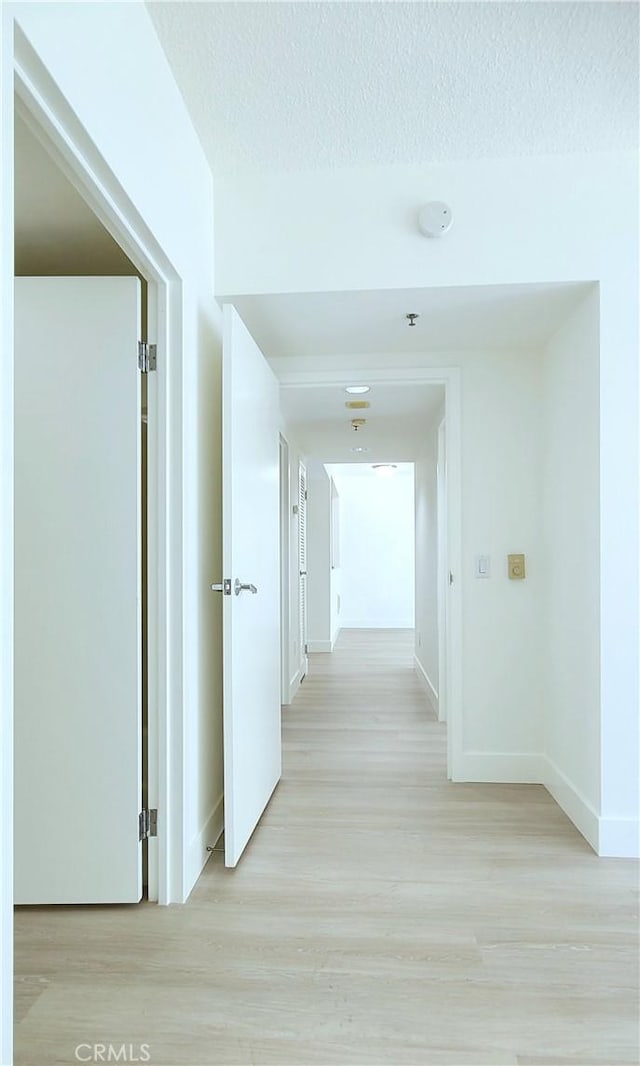 hall featuring a textured ceiling and light hardwood / wood-style flooring