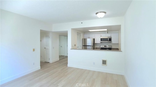 kitchen featuring kitchen peninsula, light hardwood / wood-style floors, stainless steel appliances, and white cabinetry