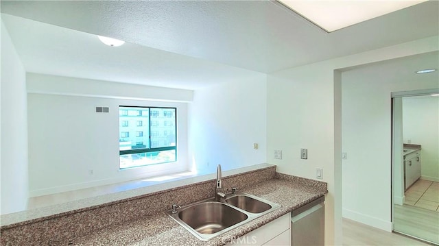 kitchen with white cabinetry, stainless steel dishwasher, and sink