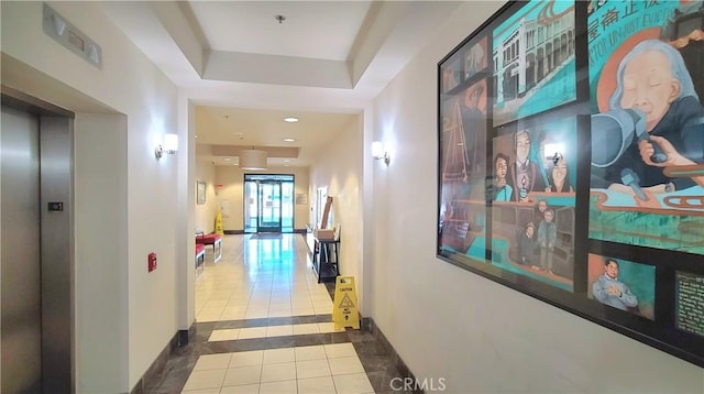 corridor featuring a raised ceiling, tile patterned flooring, and elevator