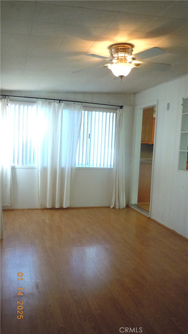 empty room with hardwood / wood-style flooring, plenty of natural light, and ceiling fan