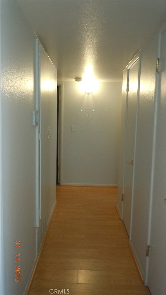 hall with a textured ceiling and light hardwood / wood-style floors