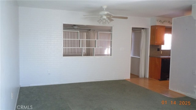 unfurnished room featuring ceiling fan, carpet, and brick wall