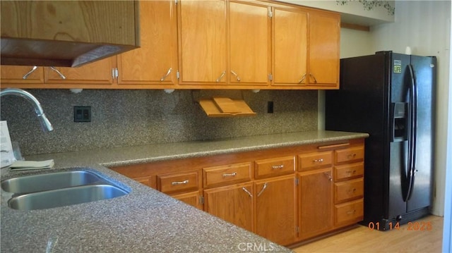 kitchen featuring tasteful backsplash, black fridge, and sink