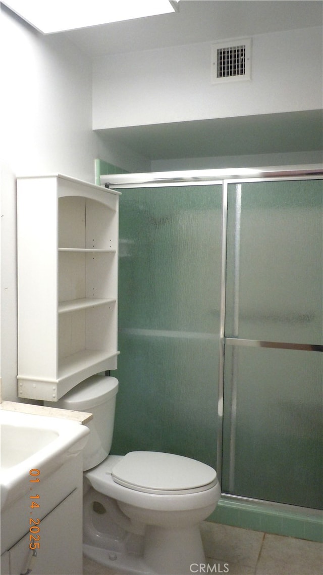 bathroom featuring toilet, vanity, tile patterned floors, and a shower with shower door