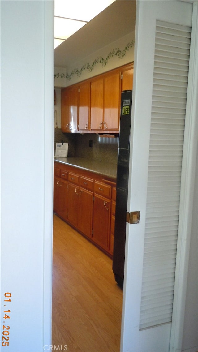 kitchen featuring tasteful backsplash, black fridge, and light wood-type flooring