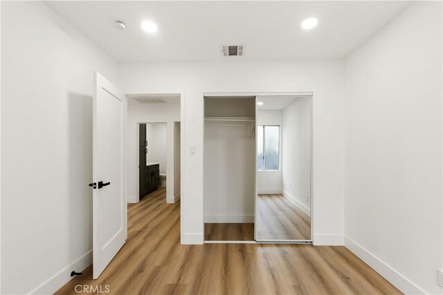 unfurnished bedroom with a closet and light hardwood / wood-style flooring